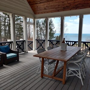 Relax on the covered deck with a wooden table and wicker furniture, taking in the views of the surrounding trees and water.