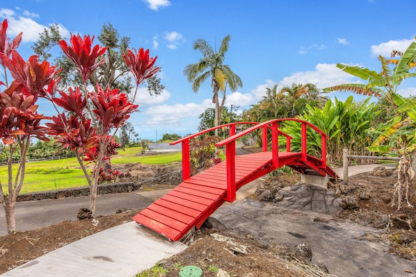 A red wooden bridge over a rocky area with a concrete path leading up to it.