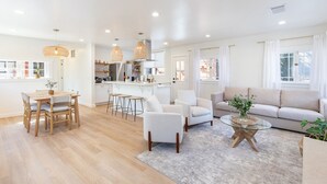 A spacious living area with a wooden dining table, white sofas, and a glass coffee table. - Your wine country getaway! (Sonoma)