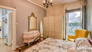 Un dormitorio con cama, cómoda, espejo, armario y una silla.