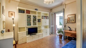 Una sala de estar con televisión, estanterías, un sofá y un comedor.