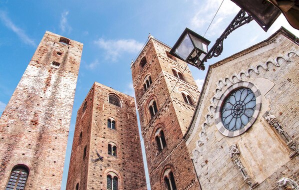 A historic building with tall brick towers and a large circular window with intricate stonework.