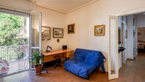 Una habitación con escritorio, sofá azul, planta en maceta y cuadros en la pared.