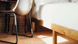 Un dormitorio con una cama de madera, una silla y una pared de ladrillo.