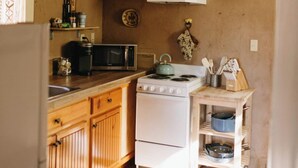 Una cocina con armarios de madera, microondas, estufa y lámparas colgantes.