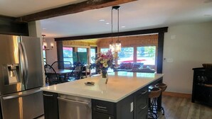 Une cuisine moderne dotée d’un grand îlot central, d’appareils électroménagers en acier inoxydable et d’un coin repas offrant une vue agréable.