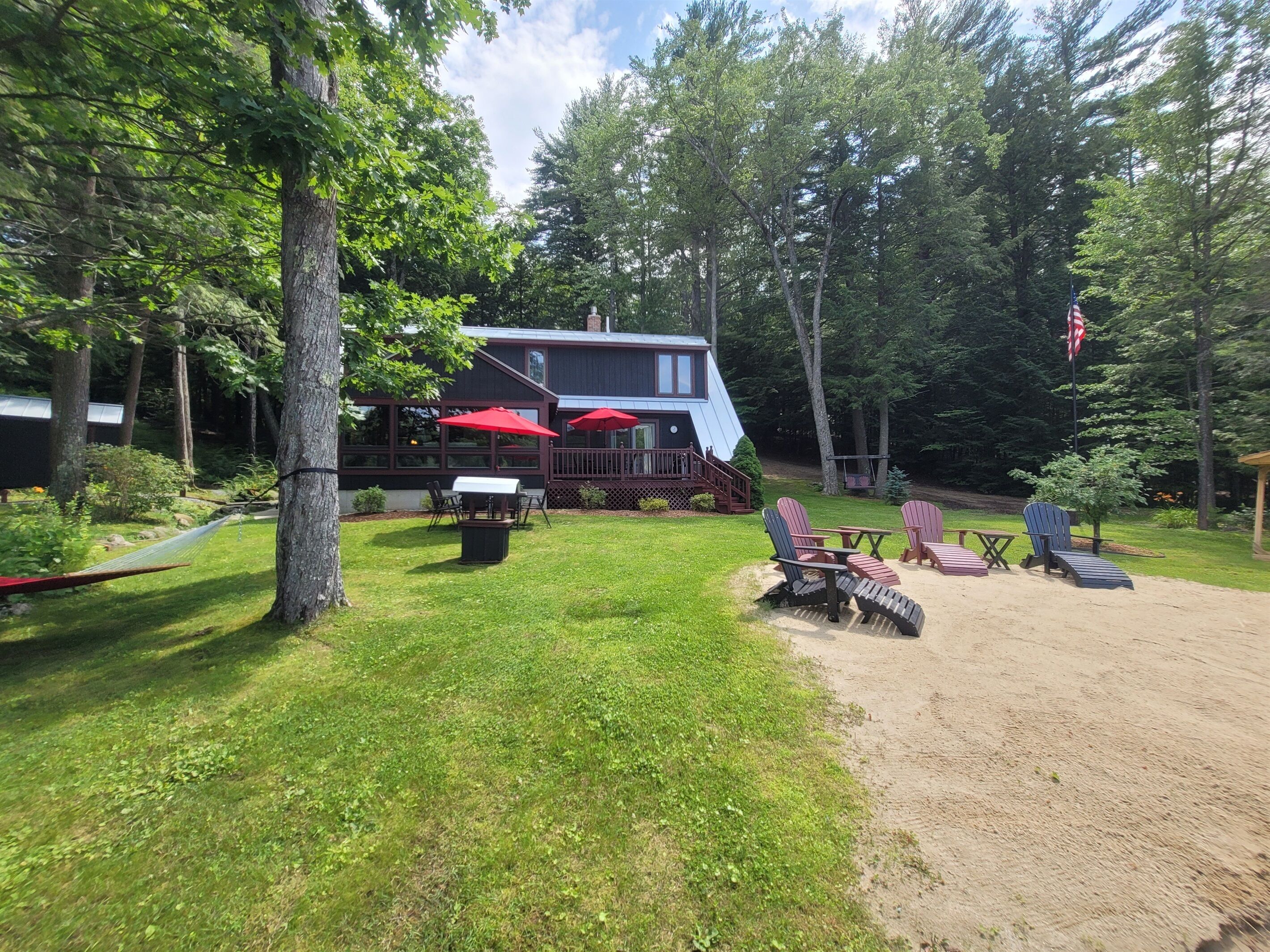 A cabin with a deck, outdoor seating, and a hammock.