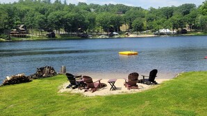 Une vue sur le lac, avec un quai, des chaises et une table sur la rive herbeuse.