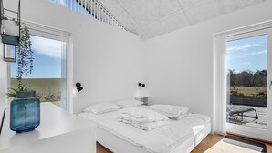 A modern bedroom with a bed, bedside tables, and a view of the outdoors.