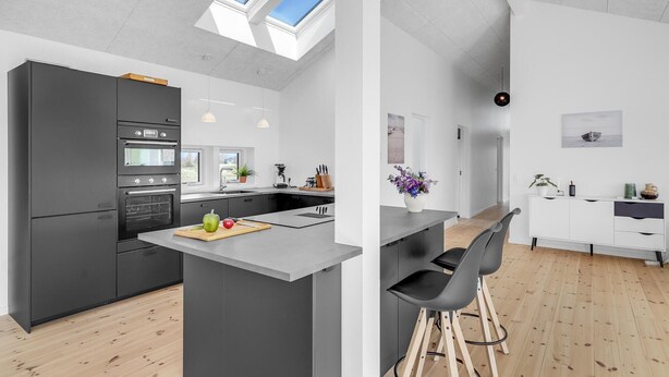 A modern kitchen with a central island, built-in appliances, and a skylight.