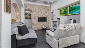 Uma sala de estar moderna com parede de pedra, televisão de tela plana, sofá, poltrona reclinável e mesa de centro.