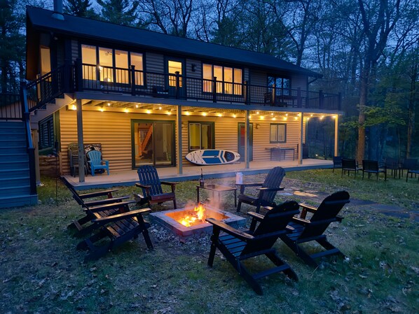Une cabane en rondins dotée d’une terrasse, de meubles de jardin et d’un foyer extérieur.