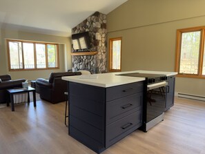 A modern kitchen with a stone accent wall, a built-in oven, and a dining area with a view of the outdoors.