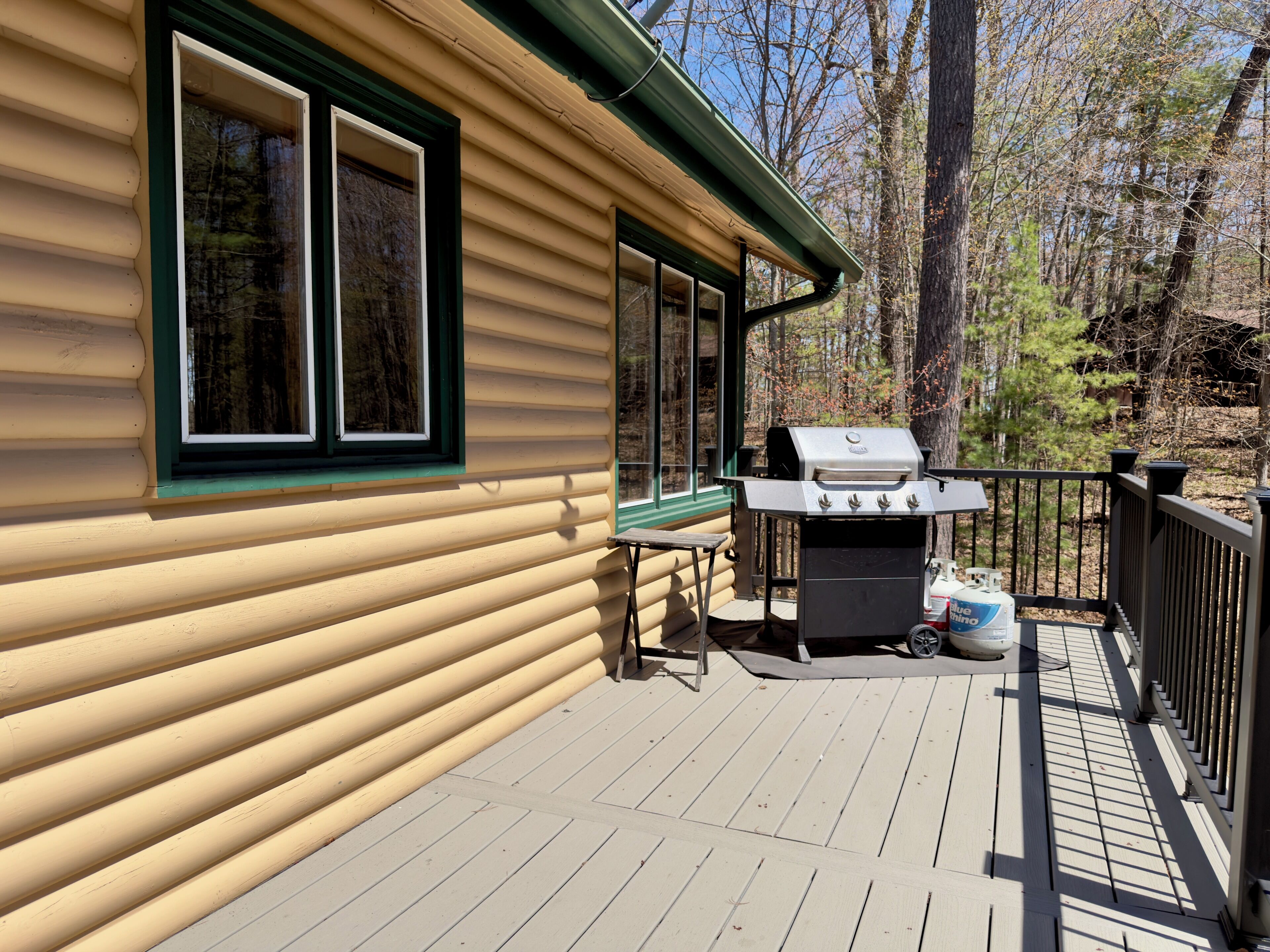 A wooden deck with a grill and outdoor seating.