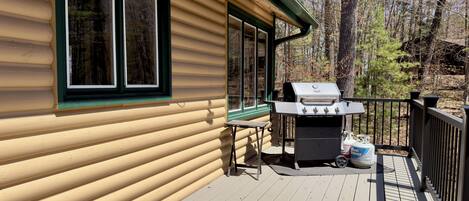 A wooden deck with a grill and outdoor seating.