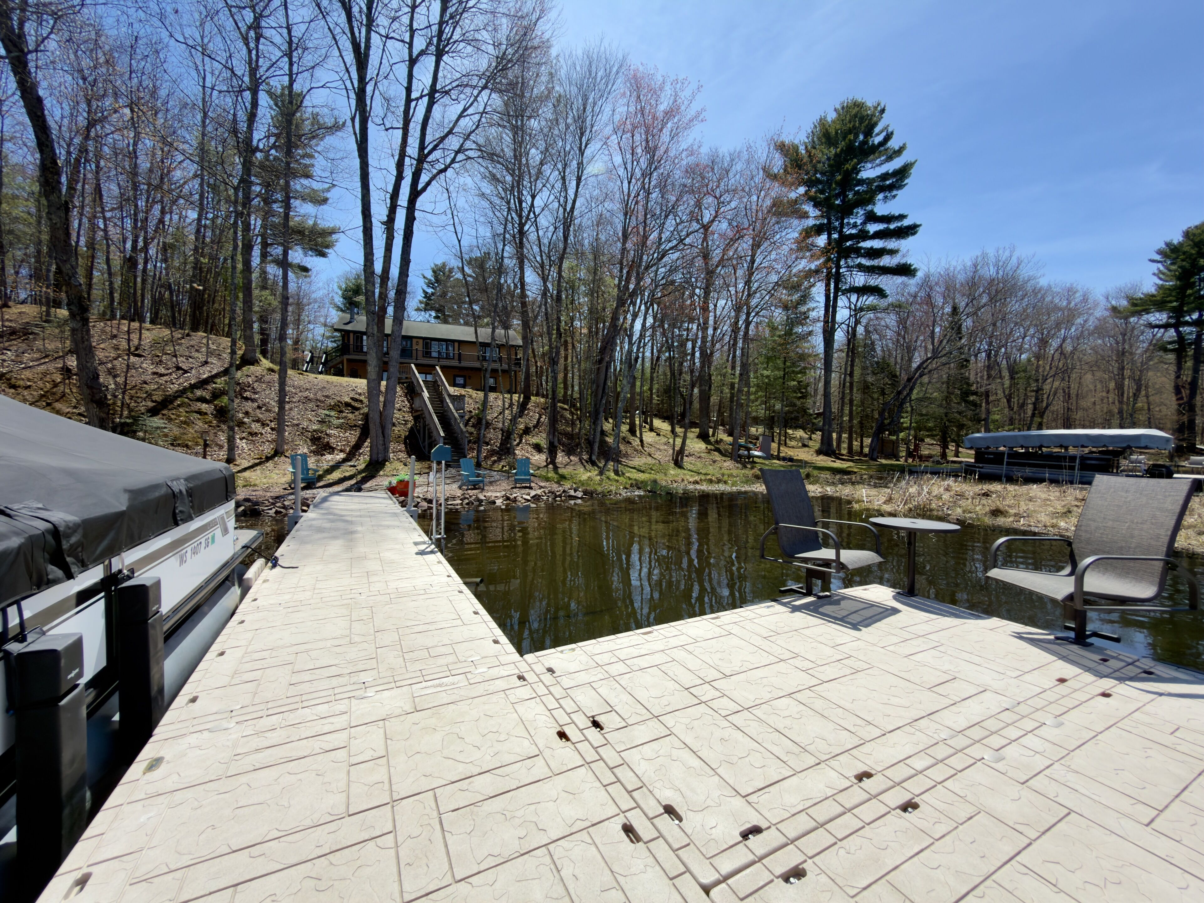 A dock with chairs and tables, a covered area, and a building in the background.