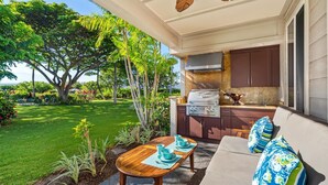 An outdoor kitchen area with a grill, dining table, and chairs. - Hilton Pool Pass 2026 and Golf Discounts. Waikoloa Beach Villas B1 (Waikoloa Beach Resort)
