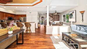 A spacious living area with a sofa, coffee table, and a dining area with chairs. - Hilton Pool Pass 2026 and Golf Discounts. Waikoloa Beach Villas B1 (Waikoloa Beach Resort)