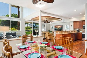 A spacious kitchen with a large island, wooden cabinets, and a dining area with a glass table and chairs.