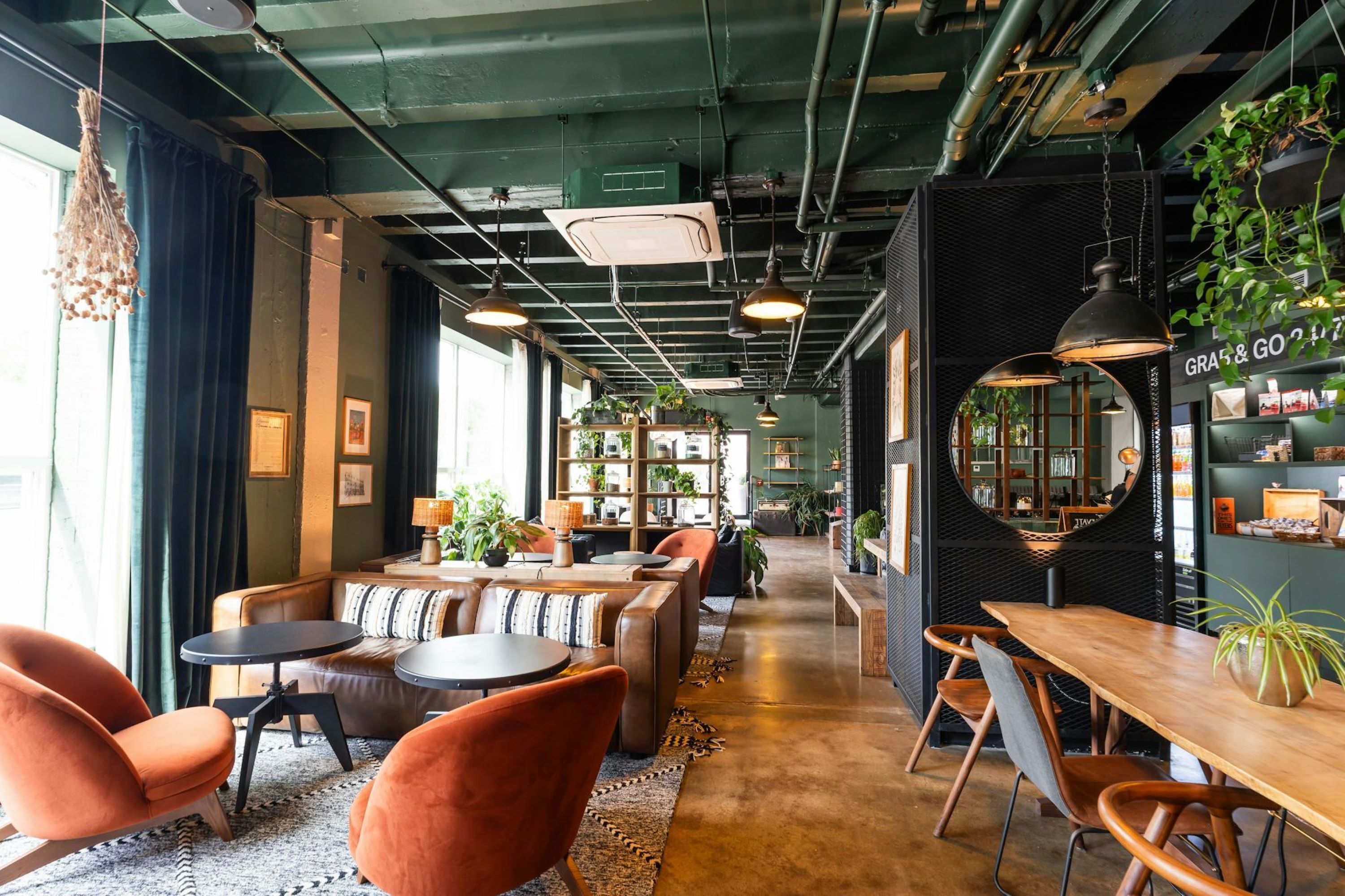 Un interior moderno con zonas de estar, mesas y una tienda visible llamada "GRASS & GO".
