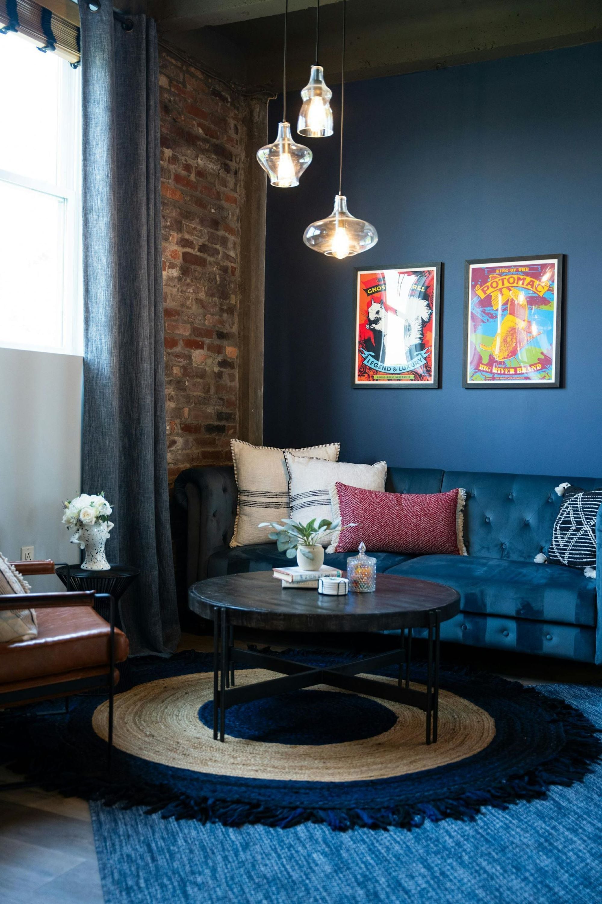 Un salon chaleureux avec un canapé bleu, une table basse ronde et un mur en briques.