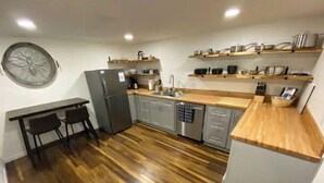 Eine moderne Küche mit Holzboden, grauen Schränken und Edelstahlgeräten.