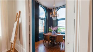 Un espace repas avec une table et des chaises en bois, un lustre et une vue dégagée grâce à de grandes fenêtres.