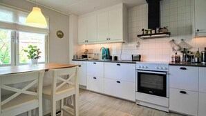 Uma cozinha moderna com armários brancos, forno embutido e uma mesa de jantar de madeira com cadeiras.