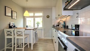 Cozinha com bancada de madeira, armários brancos e luminária pendente.