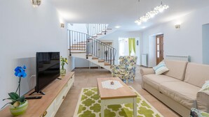 Una sala de estar moderna con televisor, sofá, mesa de centro y escalera que lleva a otra habitación.