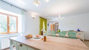 Una cocina luminosa con una isla de madera, sillas verdes y una mesa de comedor.
