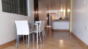 Una cocina moderna con una isla central y un comedor con sillas blancas y una mesa.