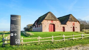 Un edificio de ladrillo tradicional con techo de paja, probablemente un sitio histórico, con un letrero que indica que forma parte de un museo nacional.