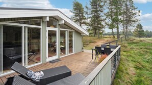 Una terraza moderna al aire libre con mobiliario de mimbre, una zona de comedor y vistas del paisaje circundante.