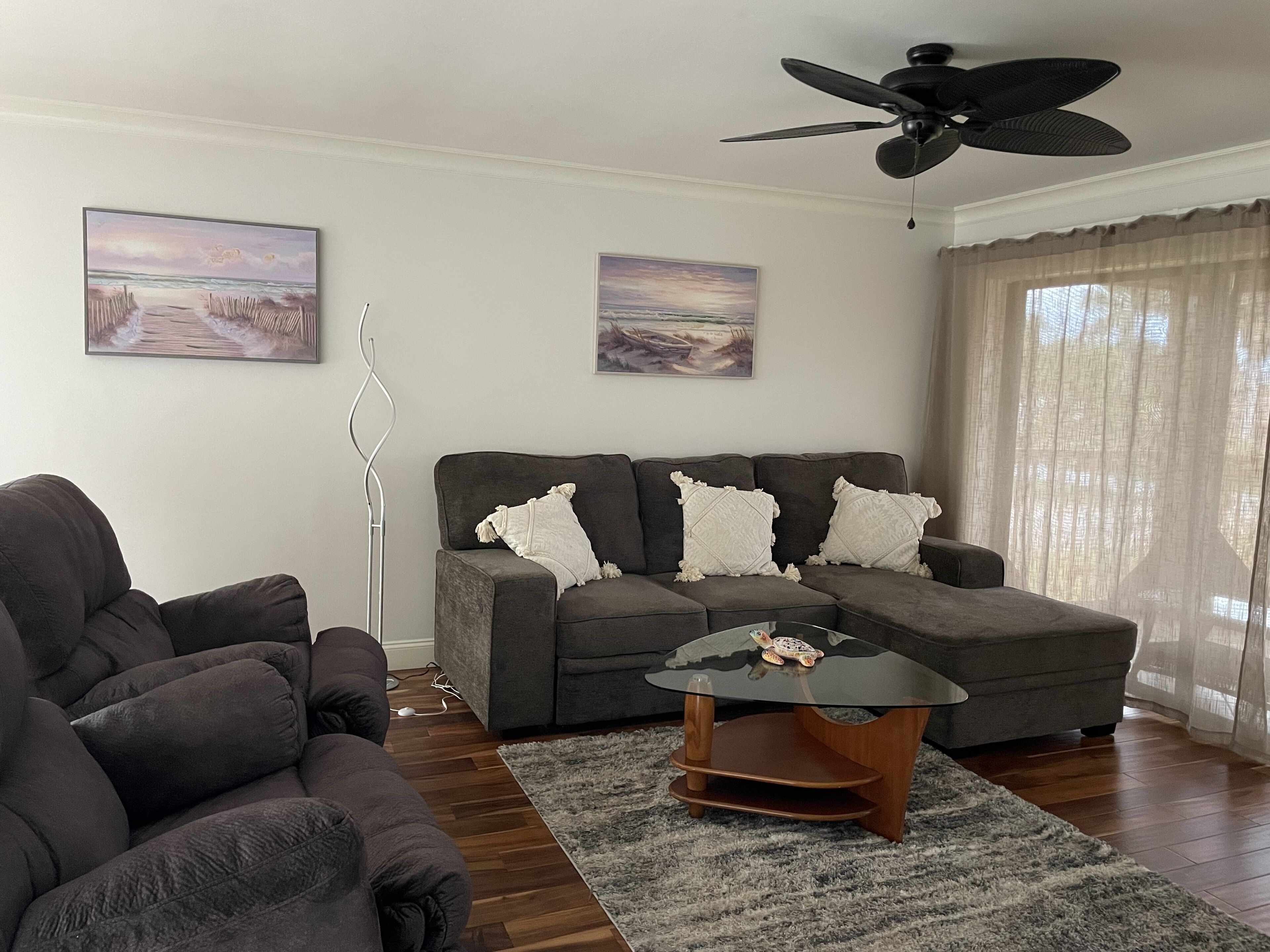 A living room with a grey sofa, a coffee table, and two paintings on the wall.