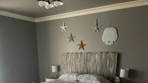 Quarto com cama, mesas de cabeceira e enfeites na parede.