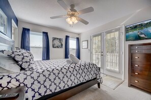 Une chambre à coucher avec un lit, un ventilateur de plafond, une commode et un téléviseur fixé au mur.