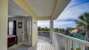 Un balcon donnant sur un quartier résidentiel, une porte menant à une chambre à coucher et un petit tapis sur le sol.
