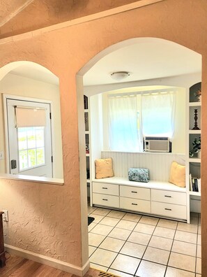 A room with a white bench, a window with a curtain, a radiator, and a tiled floor. - Cheerful 3 bedroom Corner Cottage (Jasper)