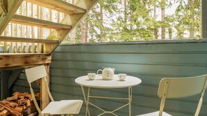 A small round table with a kettle and two cups, two white chairs, and a wooden deck with a view of trees. - ❄︎The Nest❄︎ | 1 BR 5 Min Walk to Creekside Gondola | Mountain Rustic Chic (Whistler)