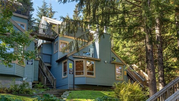 A multi-story house with a staircase leading to the upper levels, surrounded by lush greenery and trees. - ❄︎The Nest❄︎ | 1 BR 5 Min Walk to Creekside Gondola | Mountain Rustic Chic (Whistler)