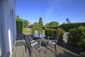 An outdoor deck with a table and two chairs, surrounded by greenery and a clear sky. - Beautiful 2-room vacation apartment with terrace - Haus Ostseeblick 1 FeWo Backbord - (Lohme)