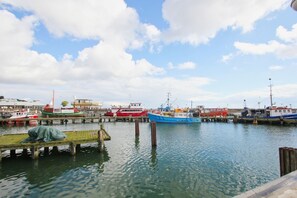 Un port où sont amarrés différents types de bateaux, avec des quais en bois et un ciel dégagé.