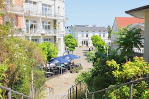 A courtyard with outdoor seating, surrounded by buildings with balconies and a red-tiled roof. - Beautiful 2-room vacation apartment with a terrace - Haus Ostseeblick 1 FeWo Steuerbord - (Lohme)
