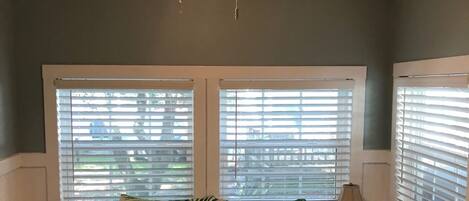 A bedroom with a bed, two nightstands, a ceiling fan, and windows with blinds.