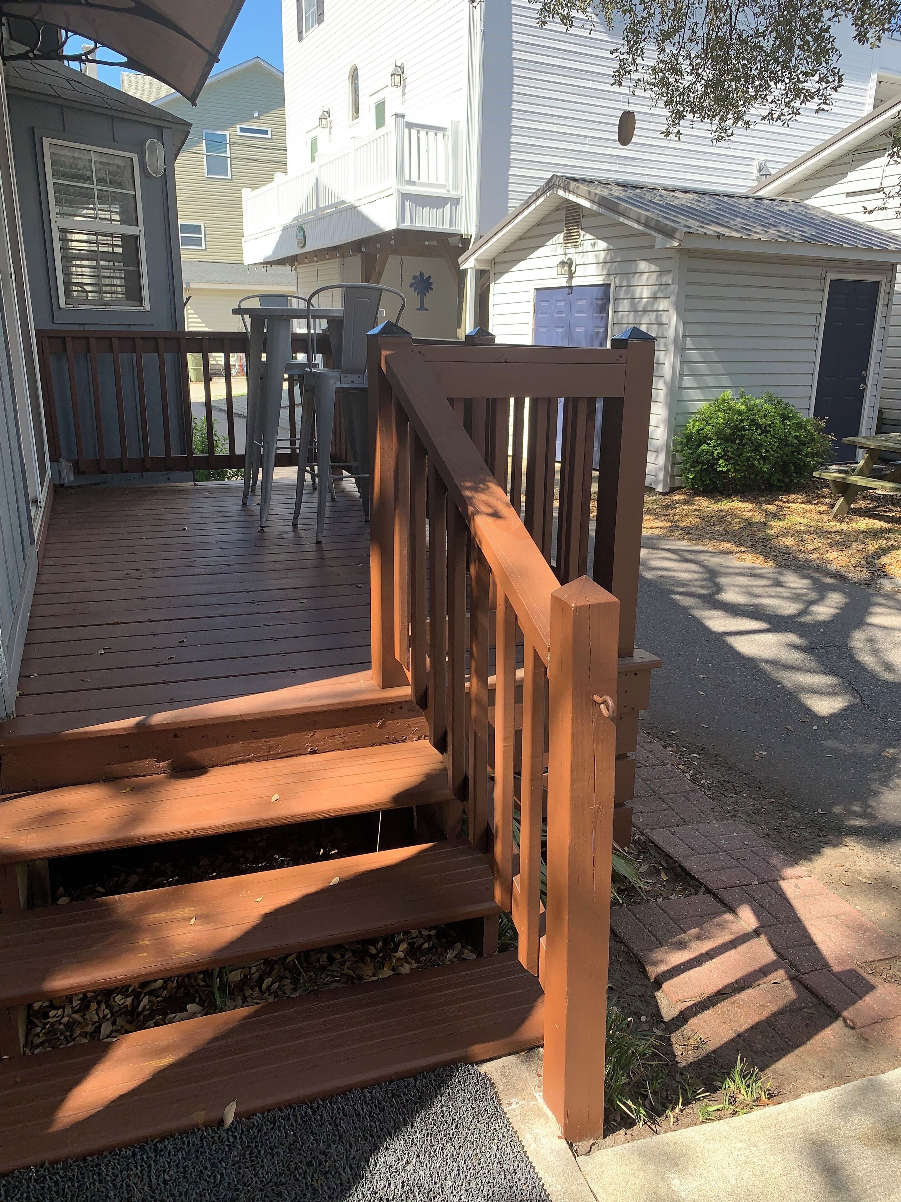Une terrasse en bois avec des marches menant à un patio couvert.
