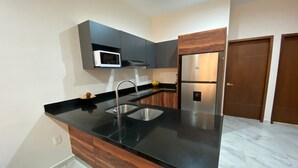 A modern kitchen with a black countertop, stainless steel sink, and built-in appliances. - New 3-Bedrooms apartment close to the beach. (Mazatlan)