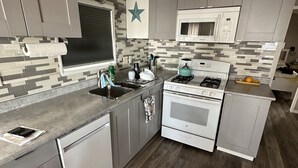 A modern kitchen with grey cabinets, a microwave, a stove, and a dishwasher.