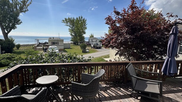 A wooden deck with wicker furniture and a view of the ocean.
