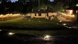 Una casa con un césped cuidado, zona de estar exterior y luces de cadena.